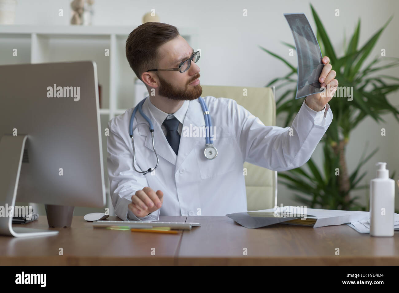 Thoughtful doctor holding chest and lungs xray in medical office Stock Photo