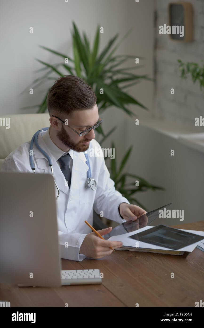 Thoughtful doctor holding chest and lungs xray in medical office Stock Photo