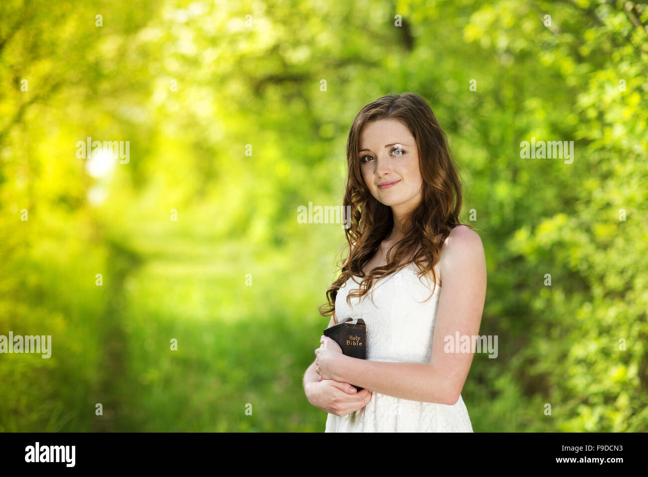 Beautiful woman with Bible is in sunny nature Stock Photo