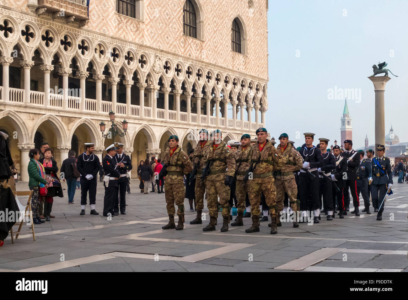 Venice, St Mark's Square. Italian soldiers march past the Doges Palace to attend to lowering of the flag ceremony at dusk Stock Photo