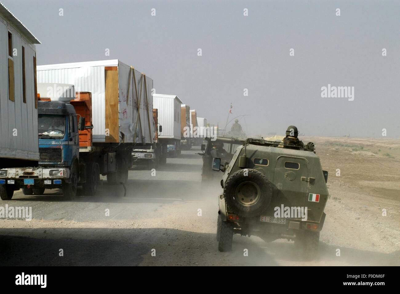 Italian military intervention in Iraq (10/2004), Italian armored vehicles encounter a restocking US truck convoy with prefabricate houses Stock Photo