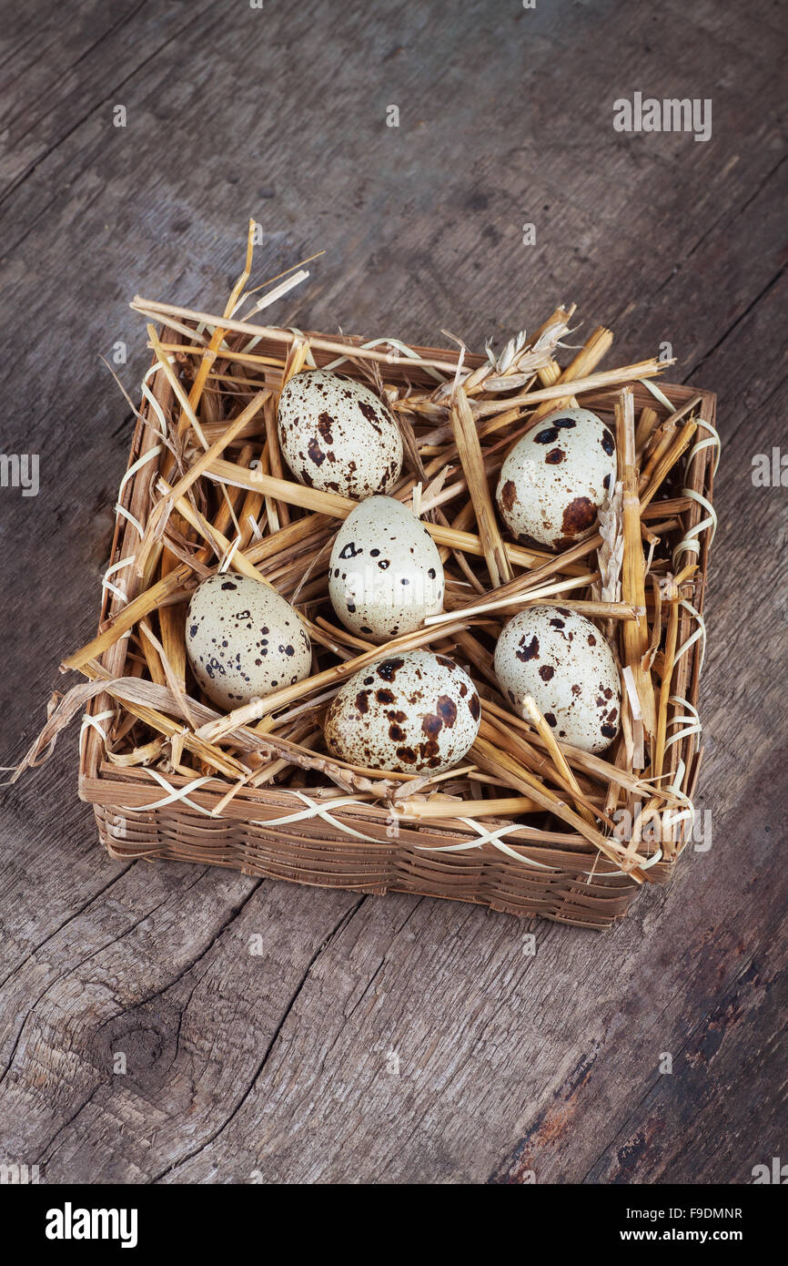 quail eggs in a wooden basket with straw on the table Stock Photo