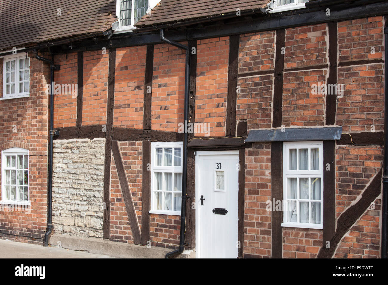 Terraced timber framed cottages where a number of brick and stone repairs have been used over the centuries, England, UK Stock Photo