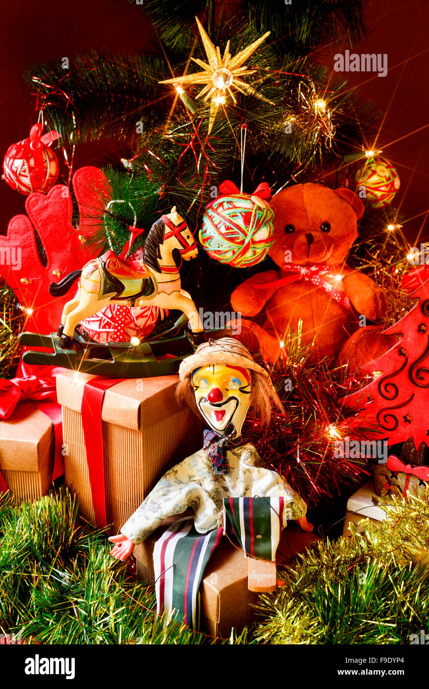 some gifts and some retro toys, such as a teddy bear, a horse or a marionette, under a christmas tree ornamented with a christma Stock Photo