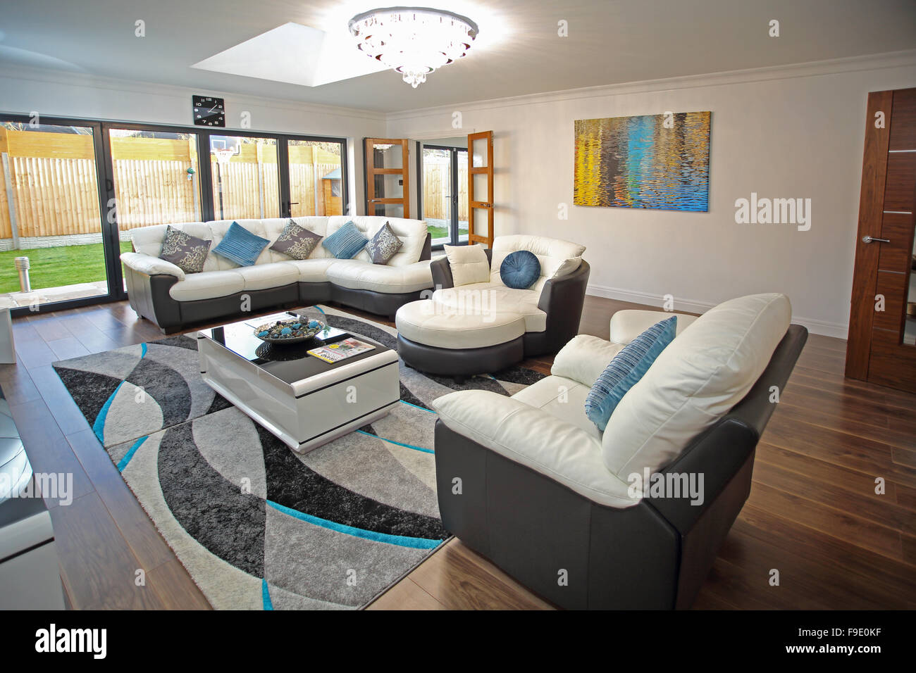 The living room of a newly refurbished house with two-tone leather sofas and bifold doors to the garden Stock Photo