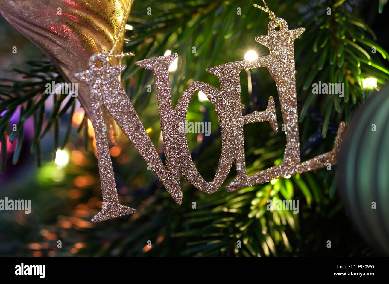 gold glitter noel sign hanging on christmas tree Stock Photo