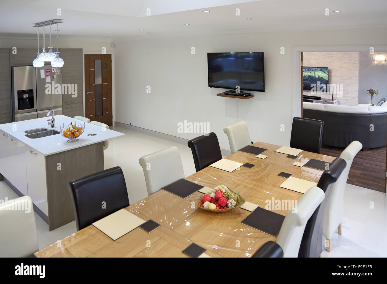 Kitchen dining room in a newly refurbished house showing living room beyond, TVs in both rooms, a plastic cover over the table Stock Photo