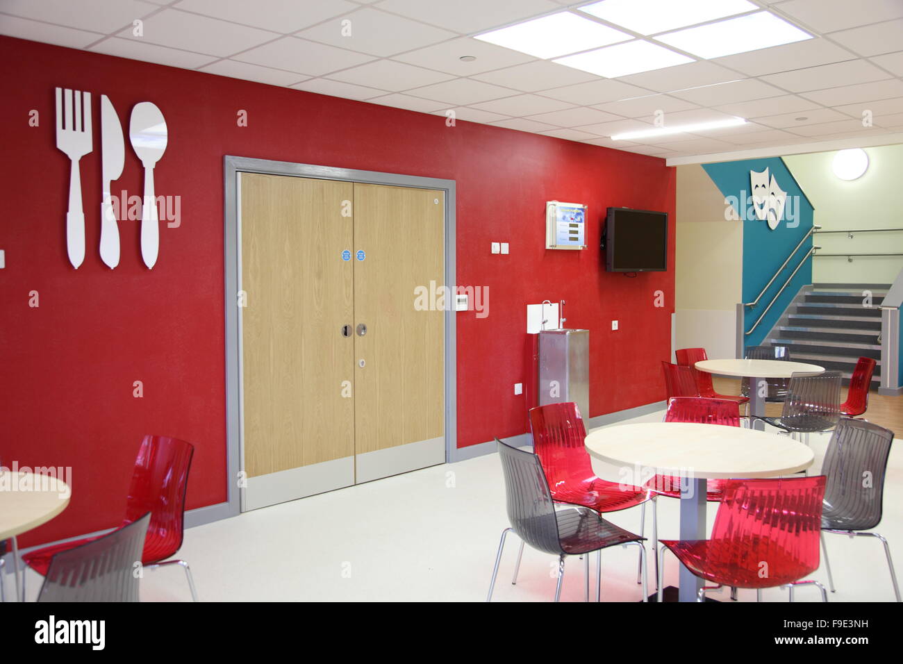 restaurant area in a new academy school featuring a red and grey colour scheme with large knife and fork symbols mounted on wall Stock Photo