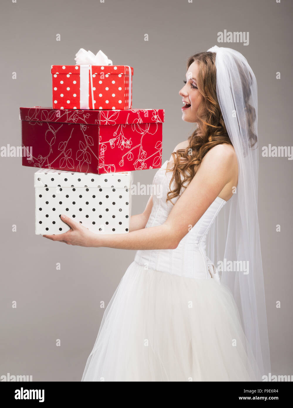 Studio portraits of beautiful bride with gift isolated on gray background Stock Photo