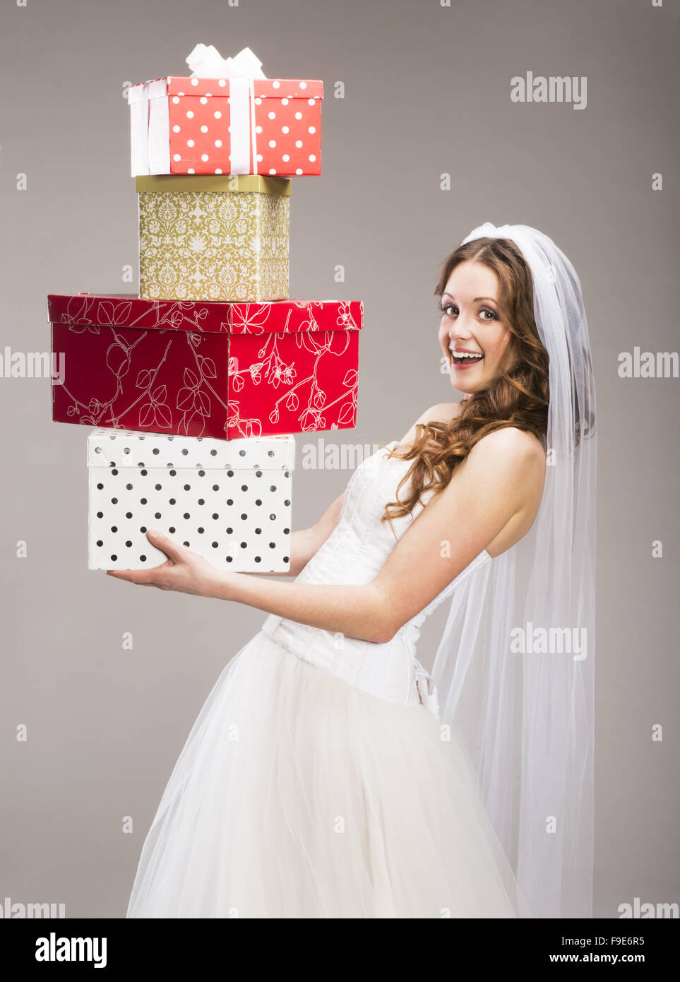 Studio portraits of beautiful bride with gift isolated on gray background Stock Photo