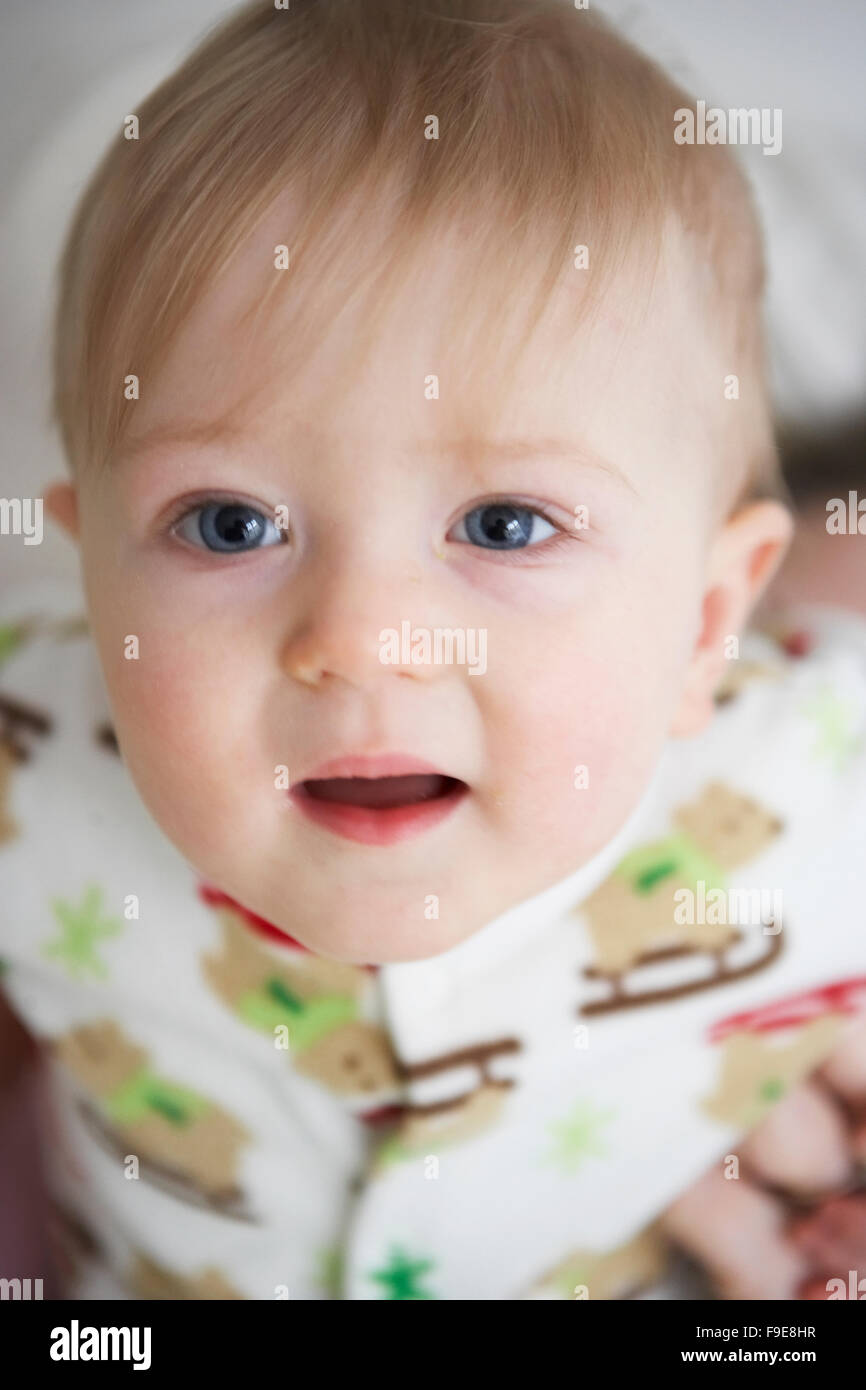 portrait of a blond blue-eyed 10-month old boy wearing a sleeper pj's babygrow Stock Photo
