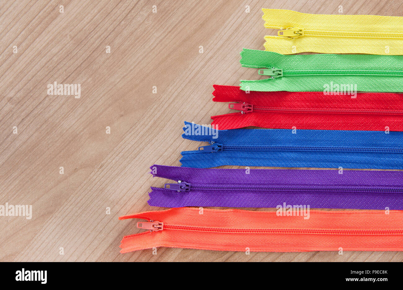 different colorful zippers in front of wood background Stock Photo