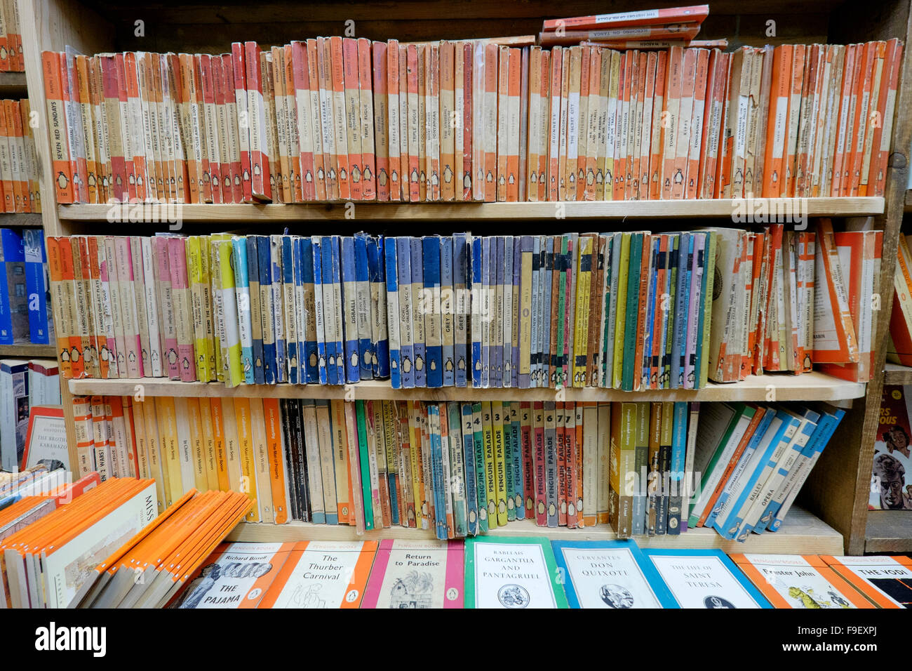 Three bookshelves of vintage Penguin paperbacks colour coded according to content e.g. orange for novels, blue for biographies Stock Photo