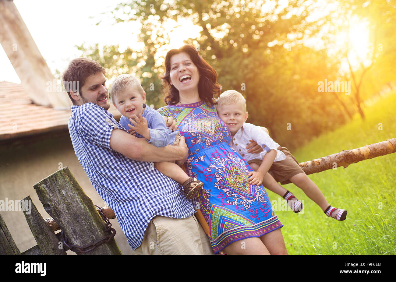 Happy young family spending time together and having fun in front of an old countryside house. Stock Photo
