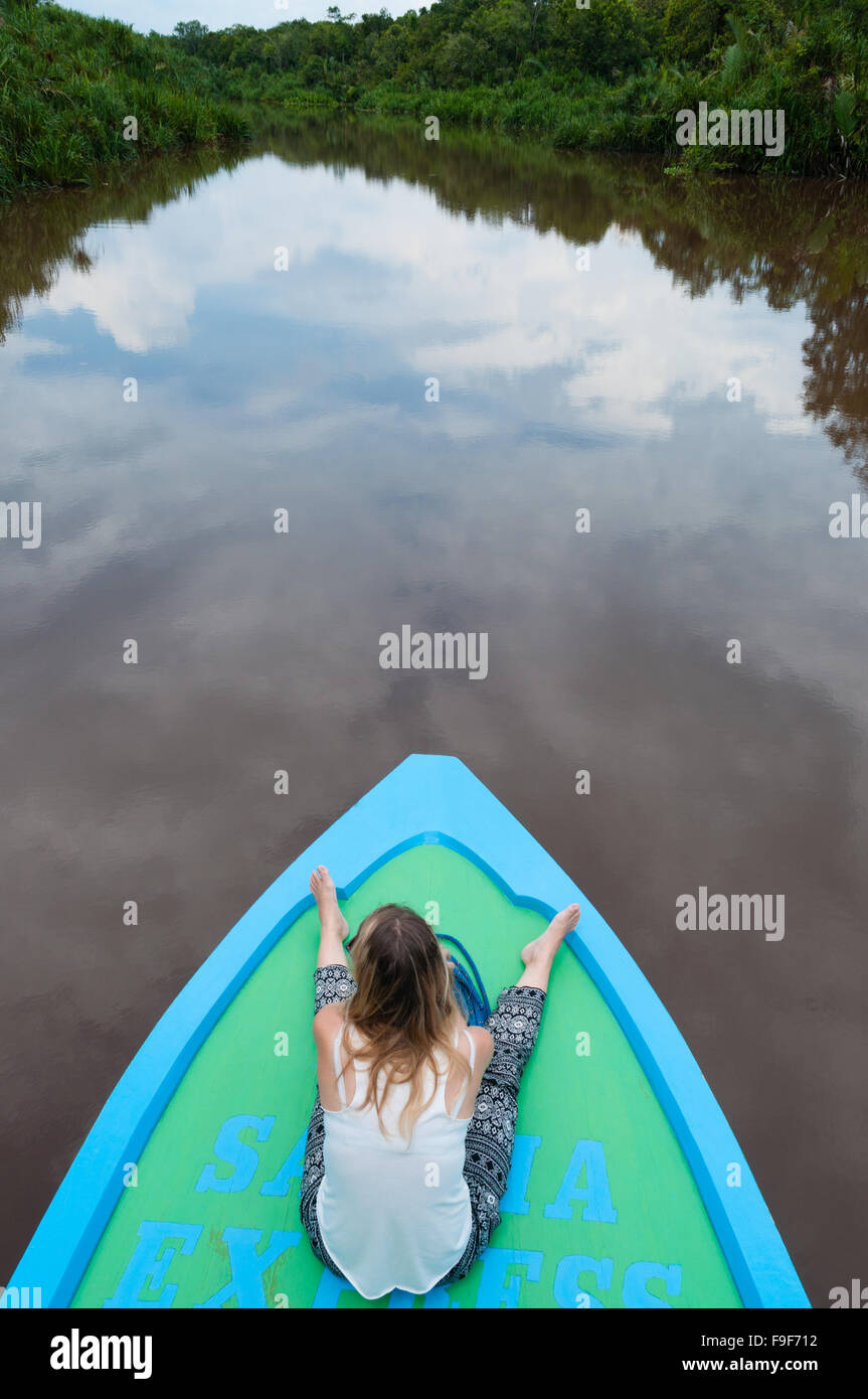 Woman on wooden boat driving river in jungle Stock Photo