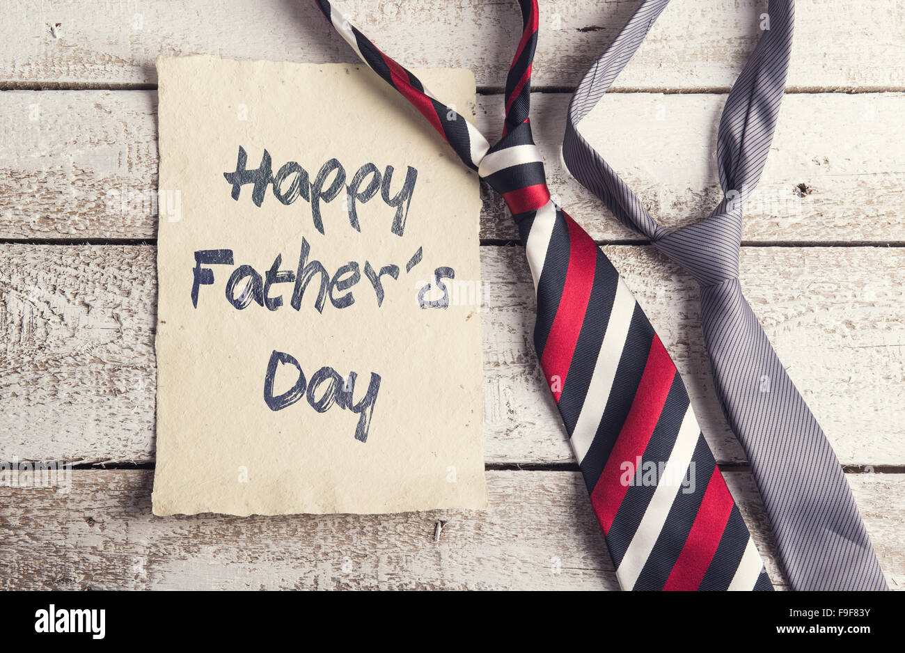 Happy fathers day sign on paper and colorful ties laid on wooden floor backround. Stock Photo