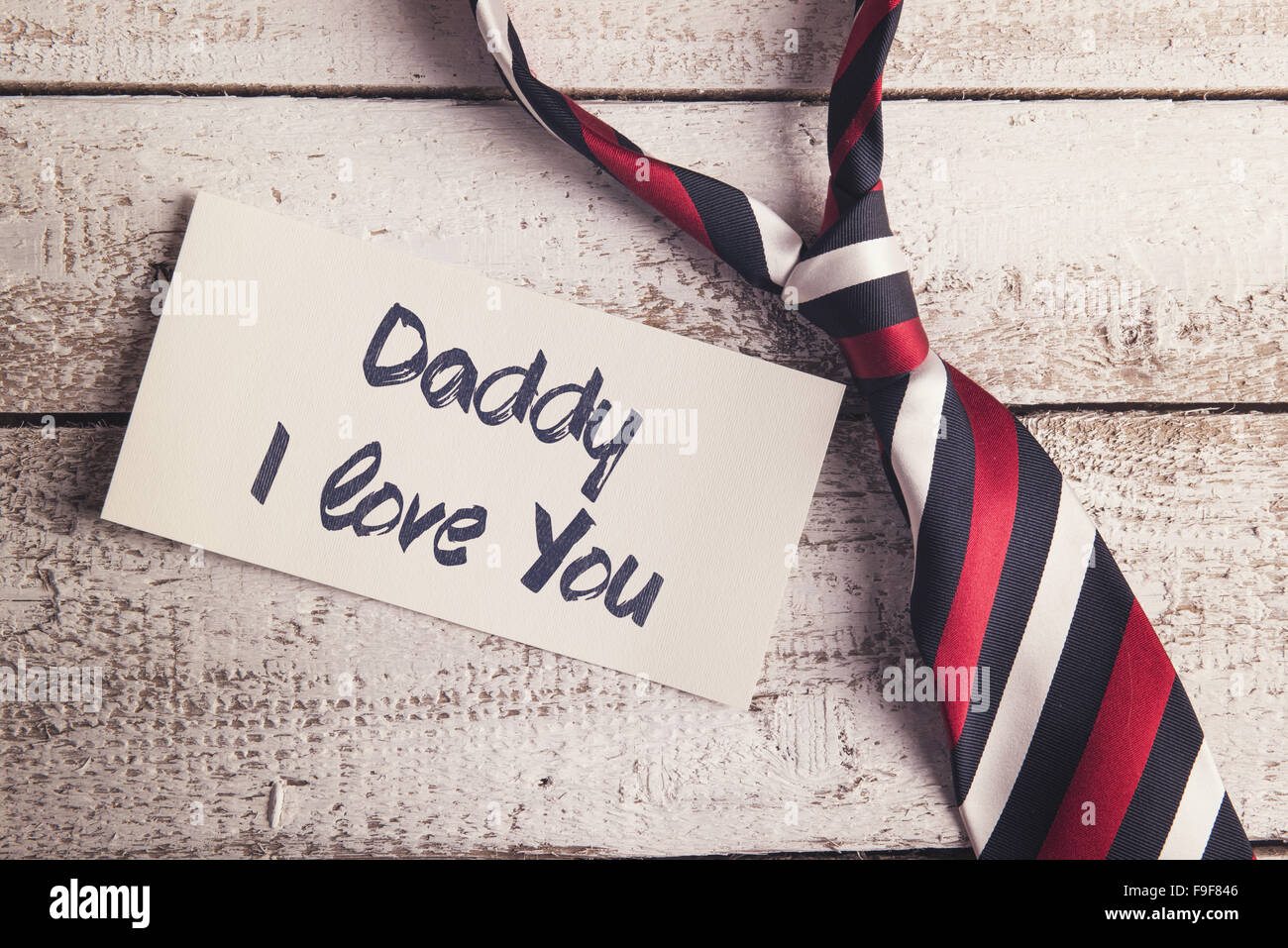 Daddy I love you sign on paper and colorful tie laid on wooden floor backround. Stock Photo
