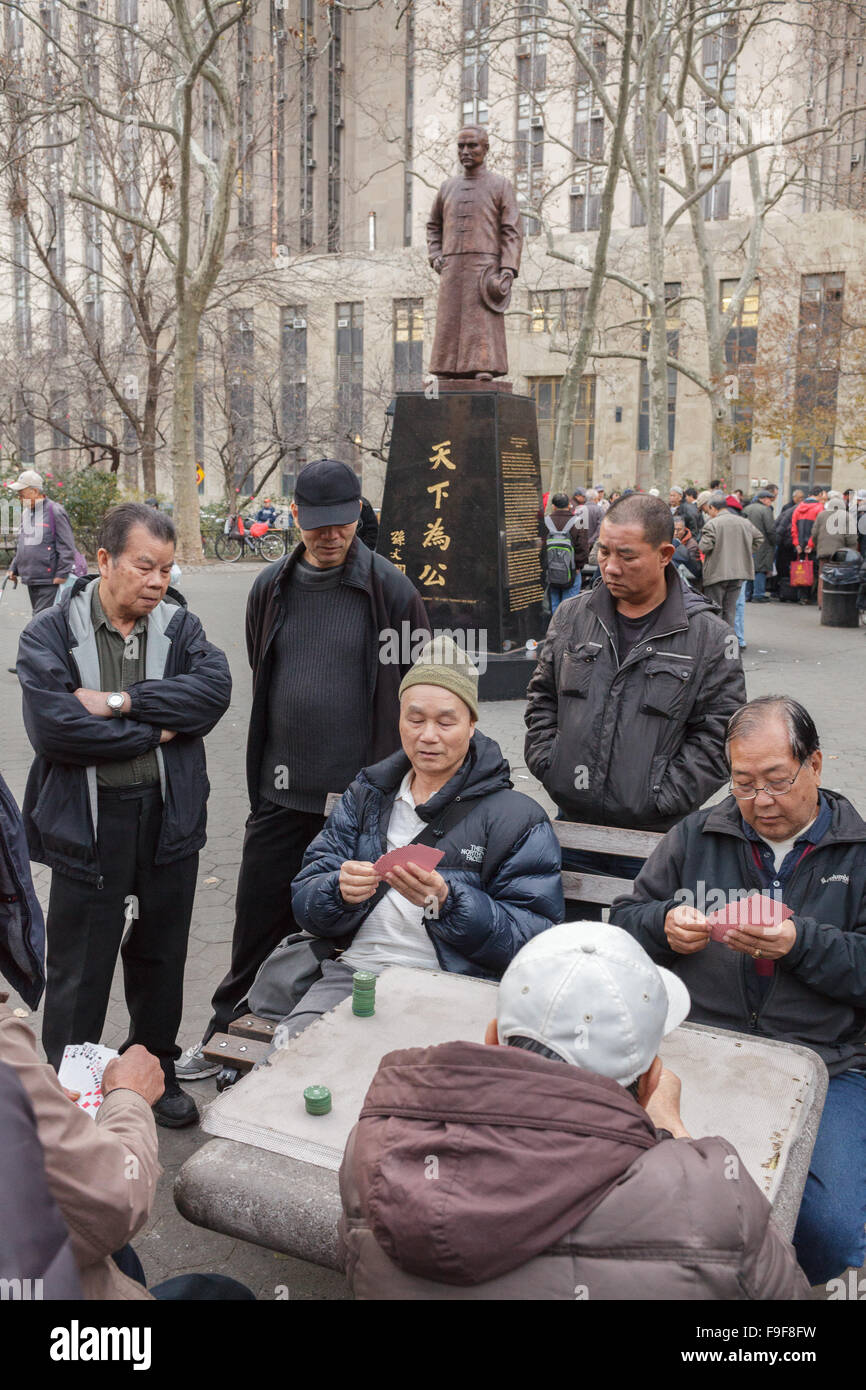 Chinese play mah-jongg board games under Dr. Sun Yat-sen statue, Columbus Park, Chinatown, New York City, USA Stock Photo