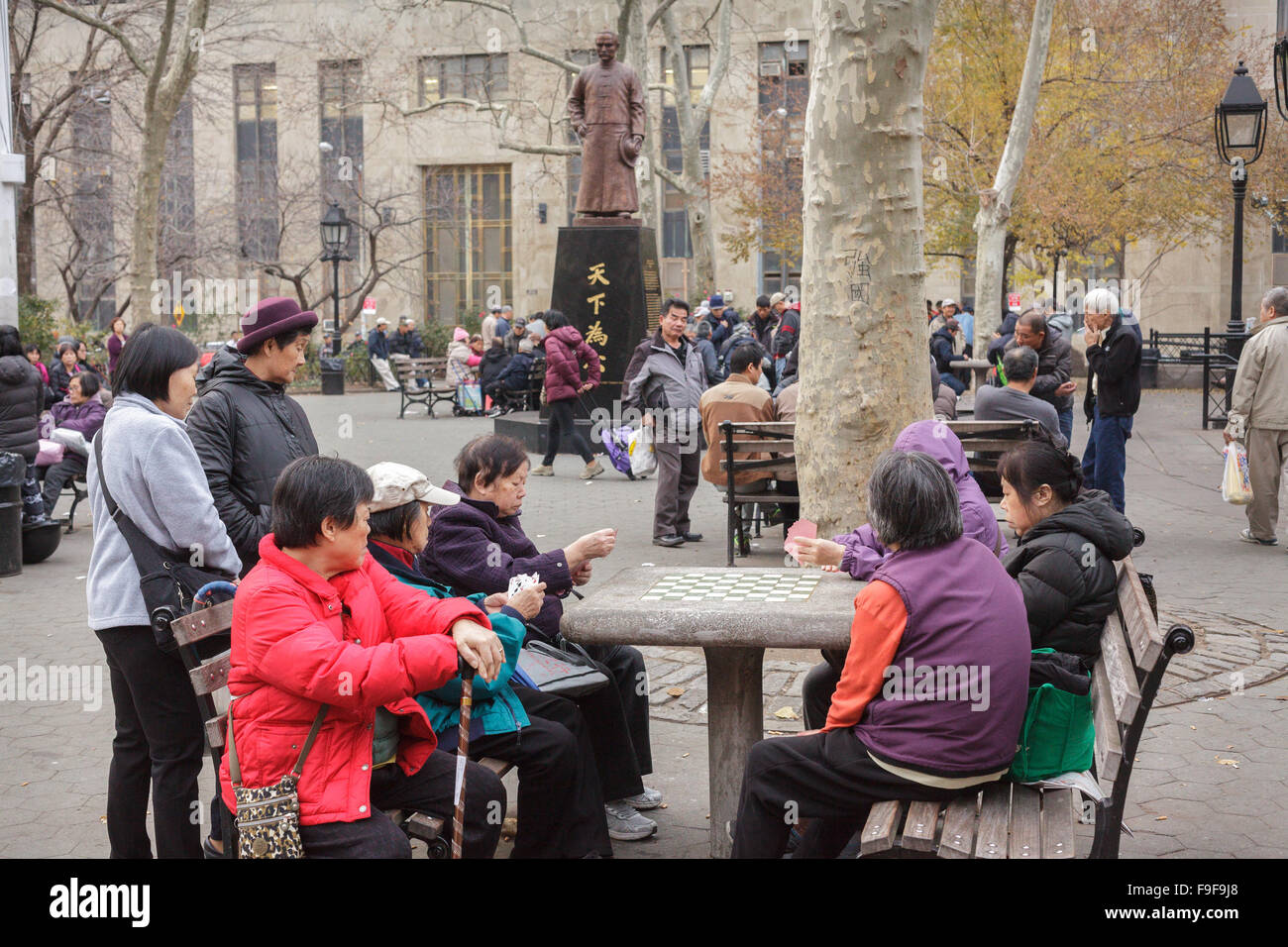 Chinese play mah-jongg board games under Dr. Sun Yat-sen statue, Columbus Park, Chinatown, New York City, USA Stock Photo