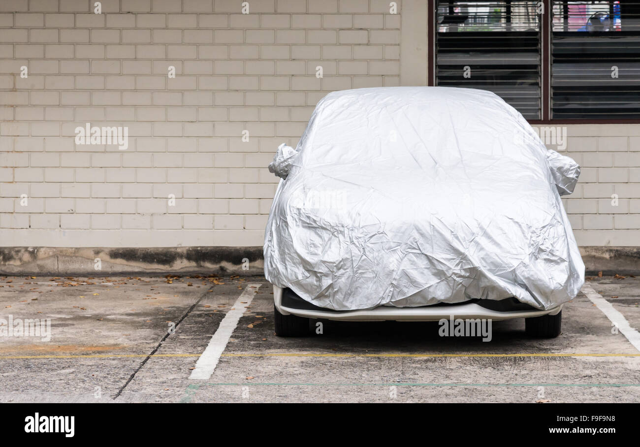 Silver cover for new car which parked in the outdoor ground. Stock Photo