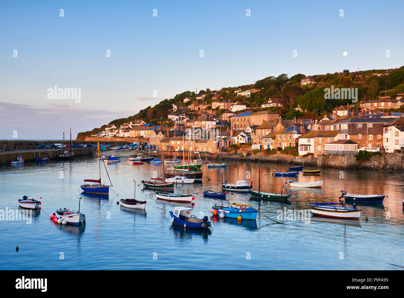 The first light of dawn catching the cottages along the waterfront, overlooking the picturesque Cornish harbour of Mousehole. Stock Photo