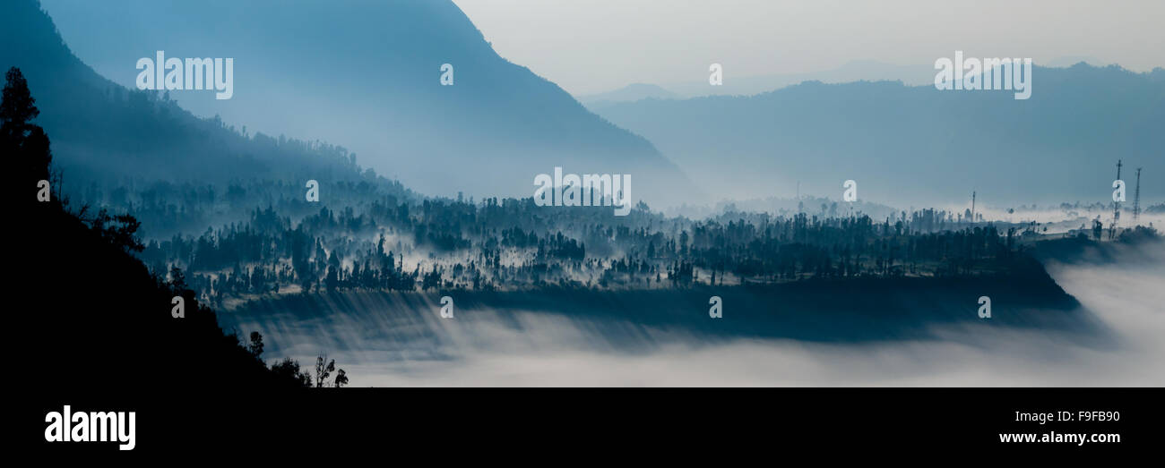 Steep black mountain silhouette in front of thick Fog Sheet Stock Photo