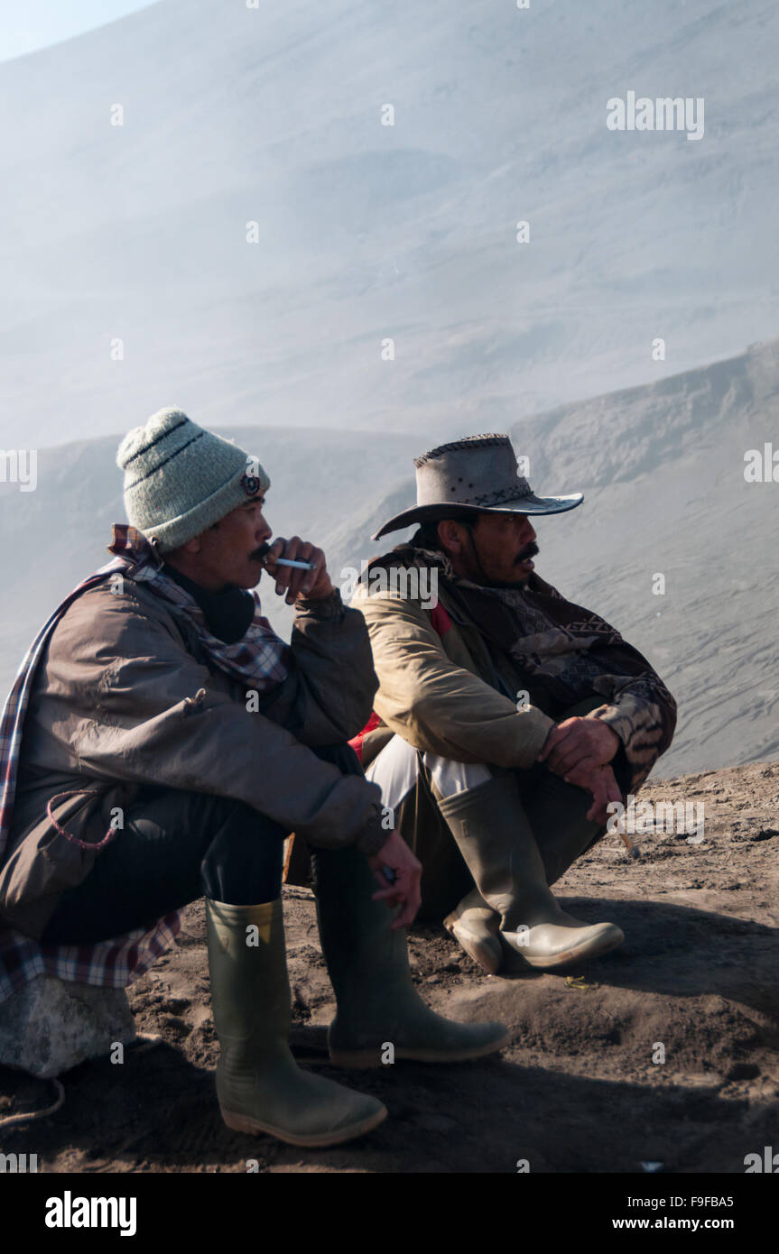 Two men resting and smoking a cigarette in front of mountain Stock Photo