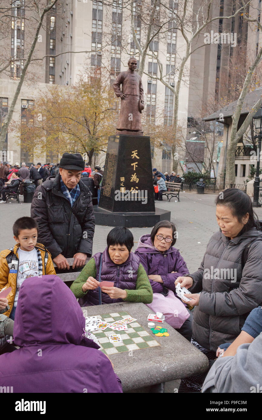 Chinese play mah-jongg board games under Dr. Sun Yat-sen statue, Columbus Park, Chinatown, New York City, USA Stock Photo