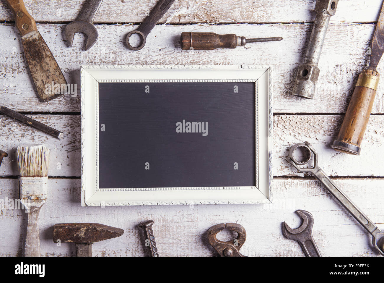 Empty picture frame and work tools. Studio shot on a wooden background. Stock Photo