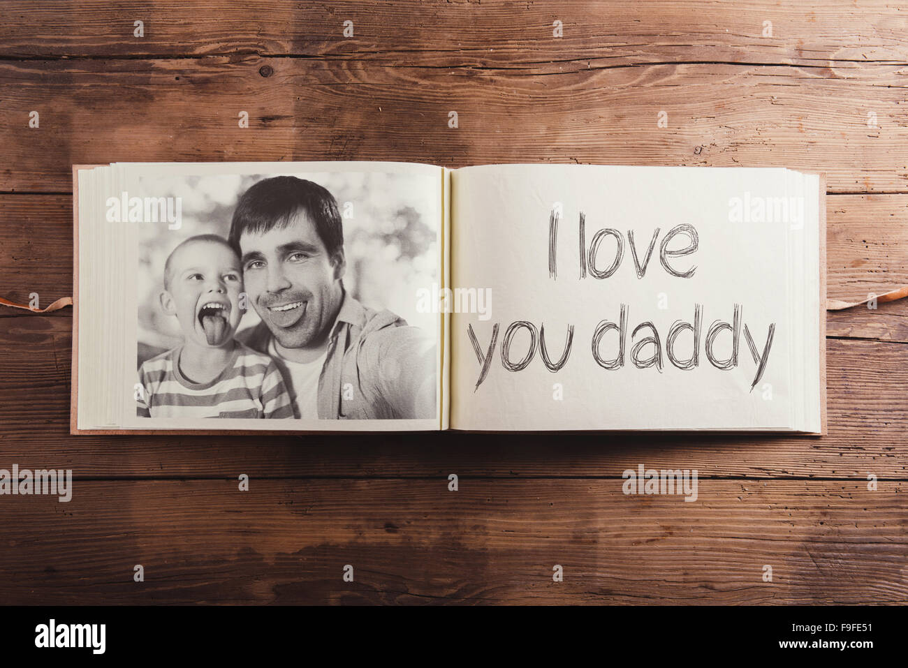 Photo album with black and white family pictures. Studio shot on wooden background. Stock Photo