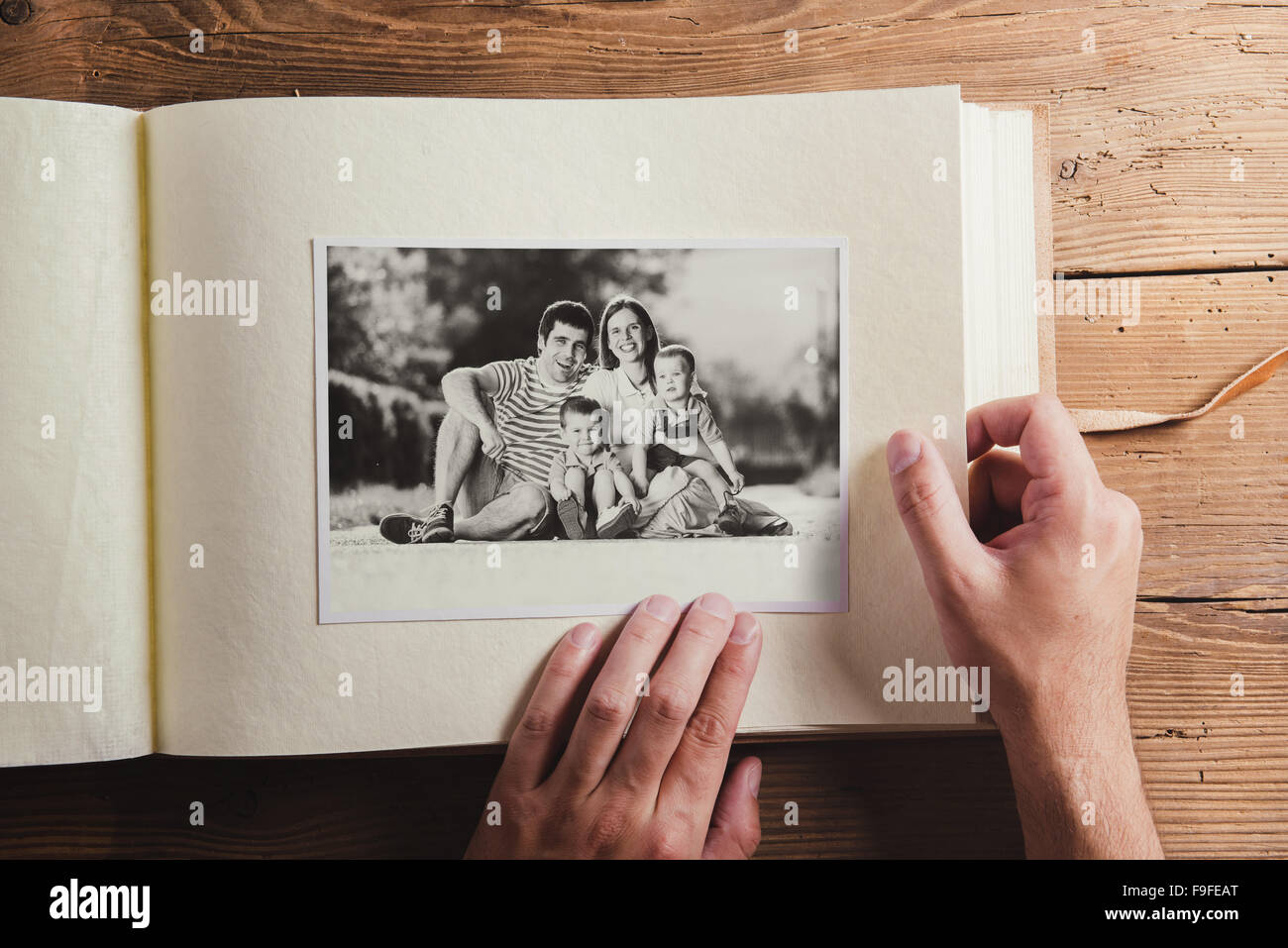 Photo album with black and white family pictures. Studio shot on wooden background. Stock Photo