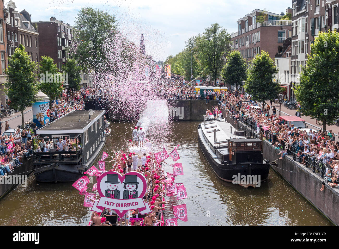 Amsterdam Gay Pride Canal Parade Festival 2015. GayMobil boat with newlywed gay couple on a Wedding Cake and Just Married sign Stock Photo