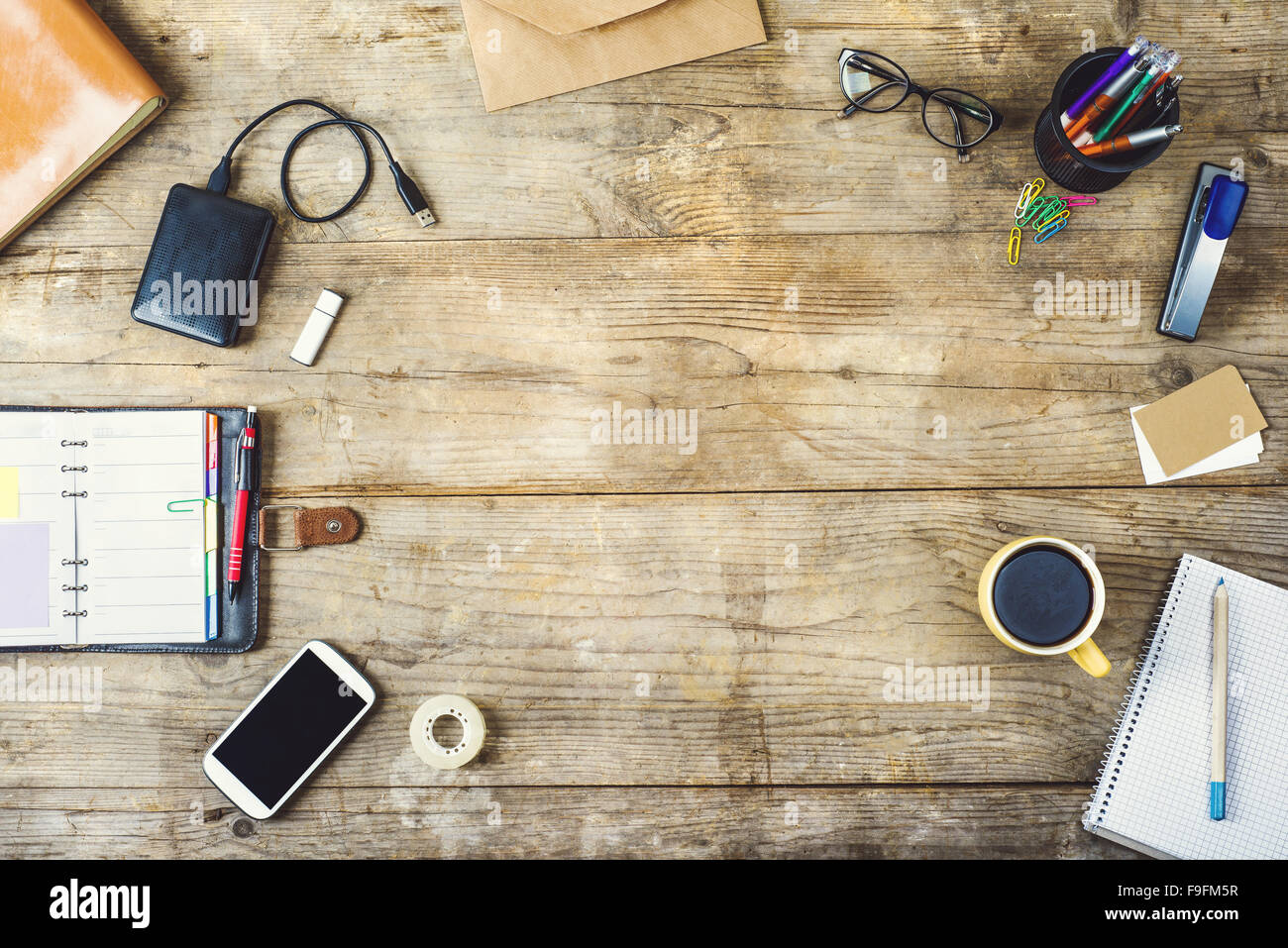 Mix of office supplies and gadgets on a wooden desk background. View from  above Stock Photo - Alamy