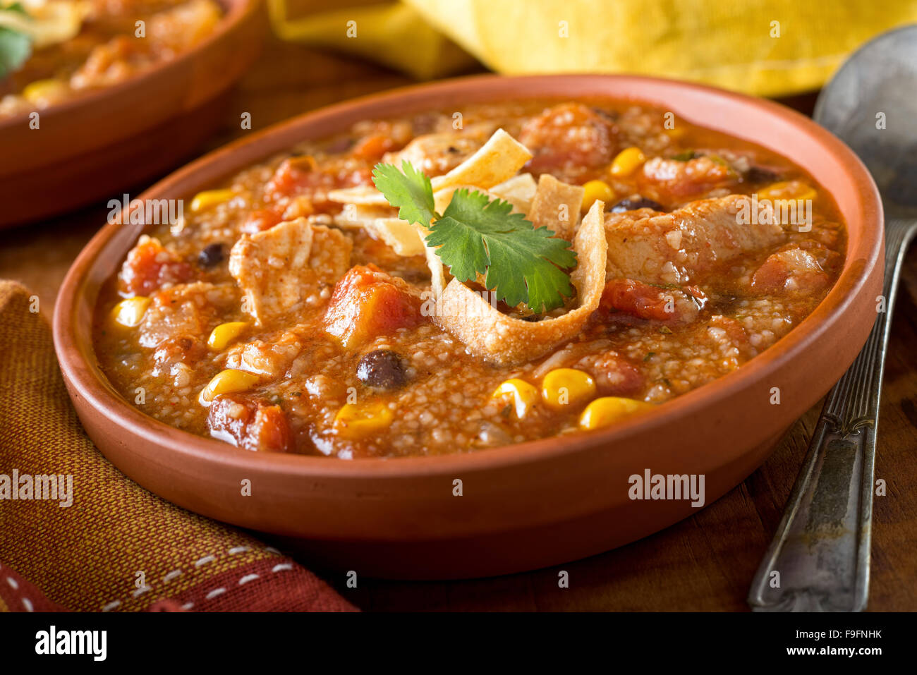 A bowl of delicious home made chicken tortilla soup with chicken, corn, black bean, tomato, hominy, and tortilla. Stock Photo