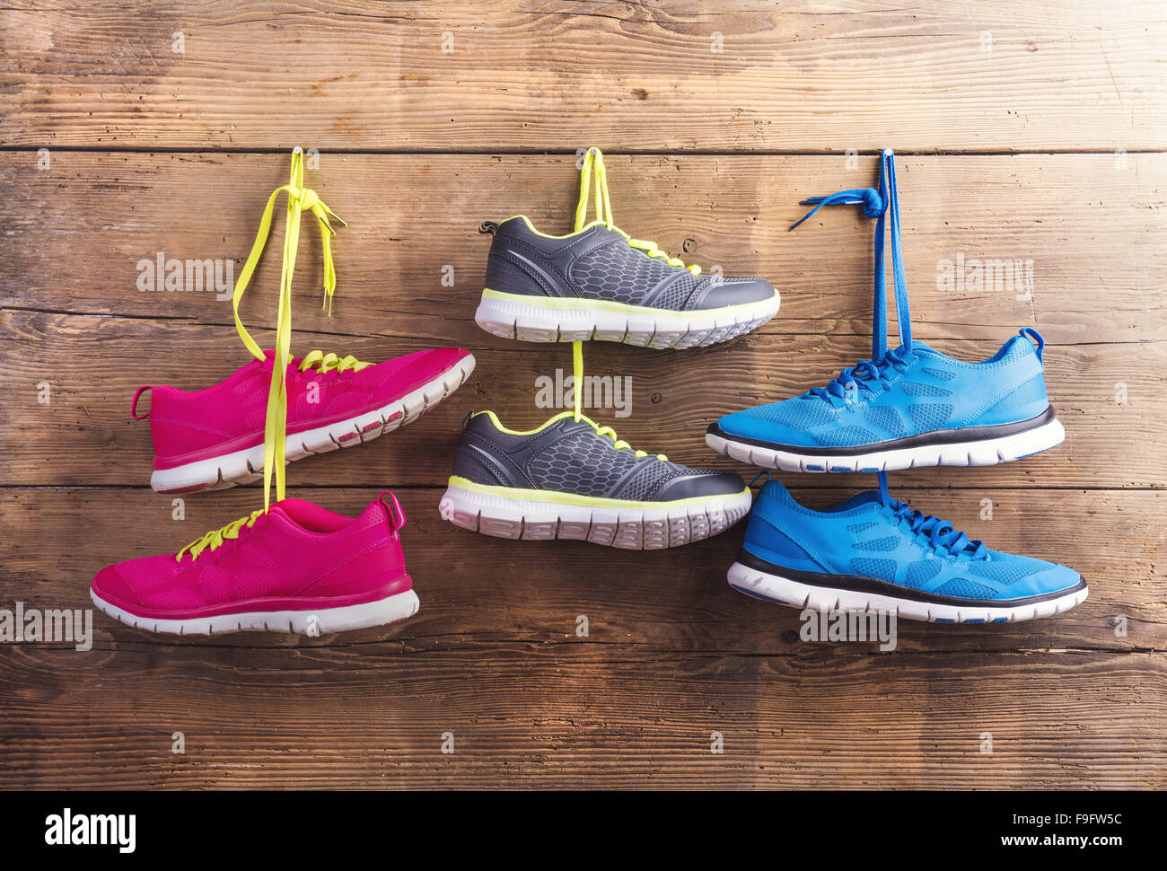 Three pairs of sneakers hang on a nail on a wooden fence background ...