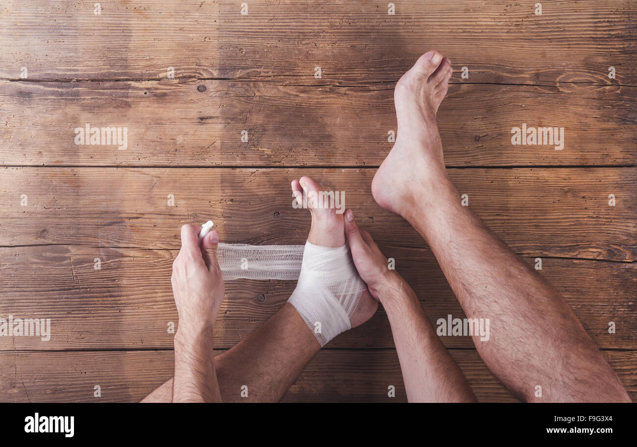 Unrecognizable injured runner sitting on a wooden floor background Stock Photo