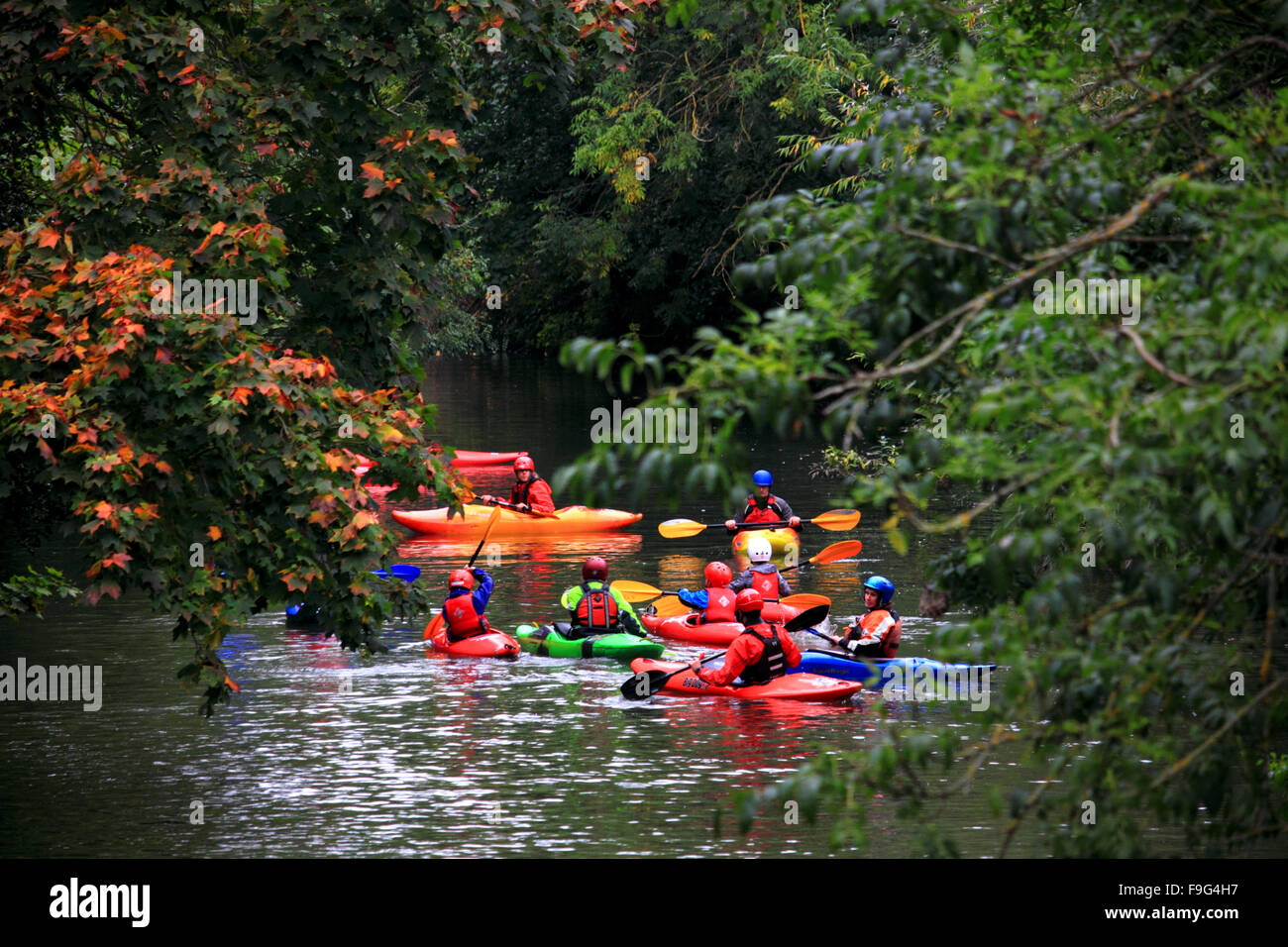 Canoeists wearing red lifejackets and helmets on the River Leam, Leamington Spa, Warwickshire. Stock Photo