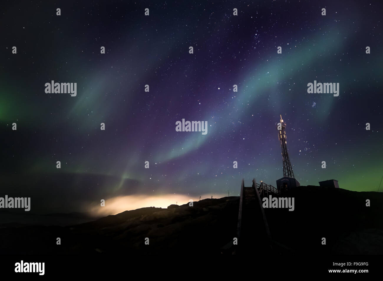 Green extensive Northern lights shining over the starlight sky and telecommunication tower, Nuuk, Greenland, October 2015 Stock Photo