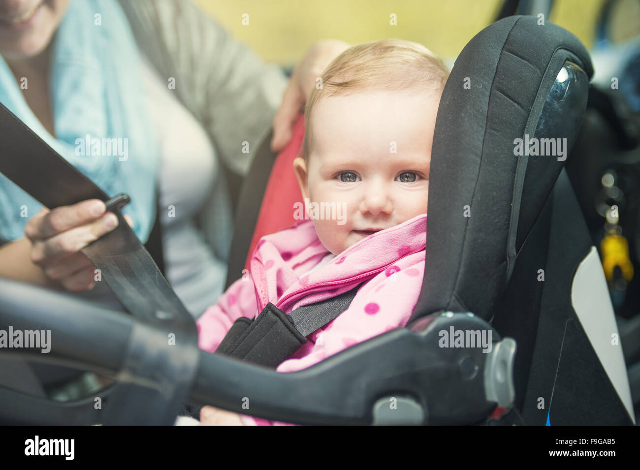 Mother in a car, having her little baby girl in a child seat Stock Photo