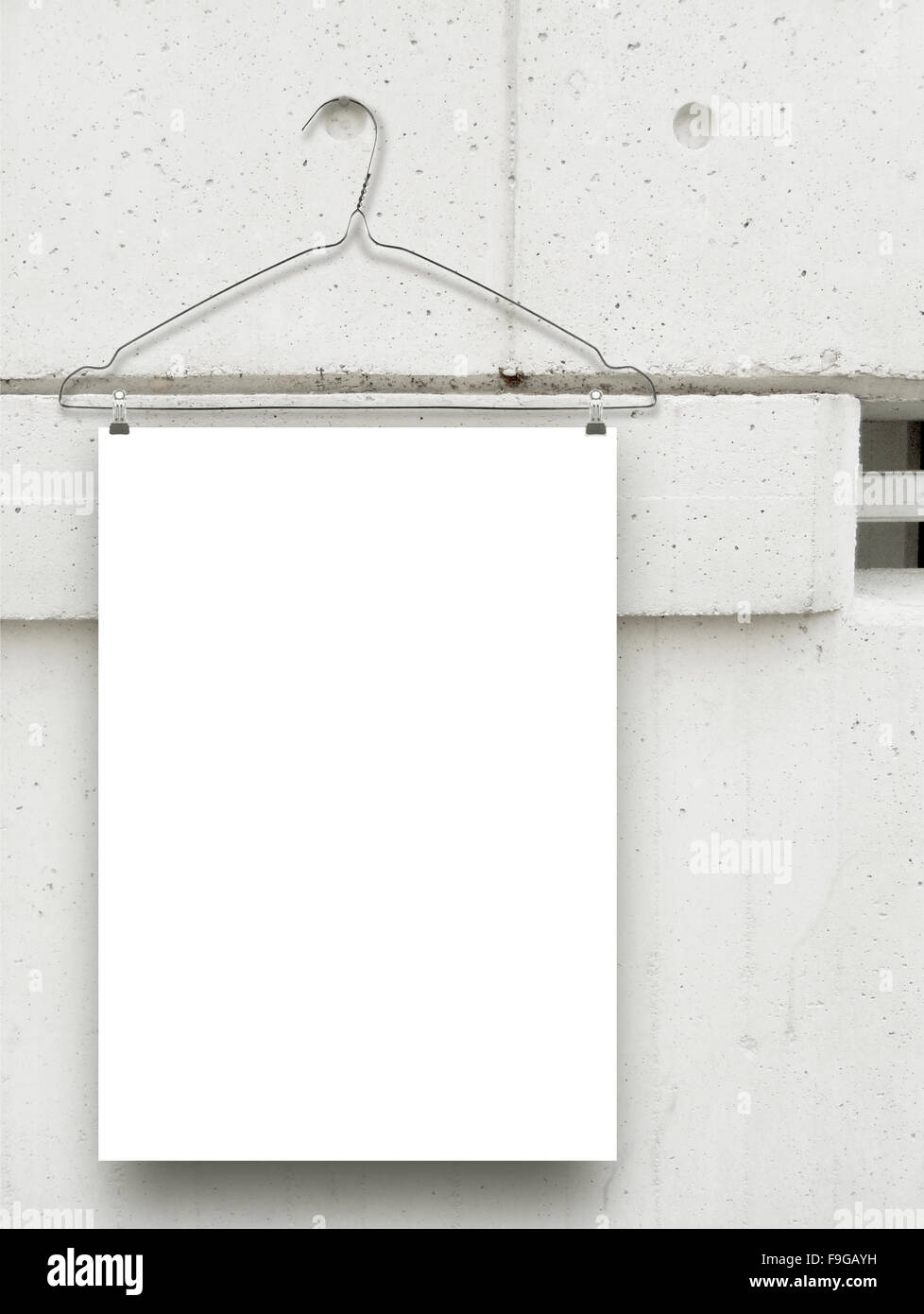 Close-up of white paper sheet frame with clothes-hanger on grey concrete wall background Stock Photo