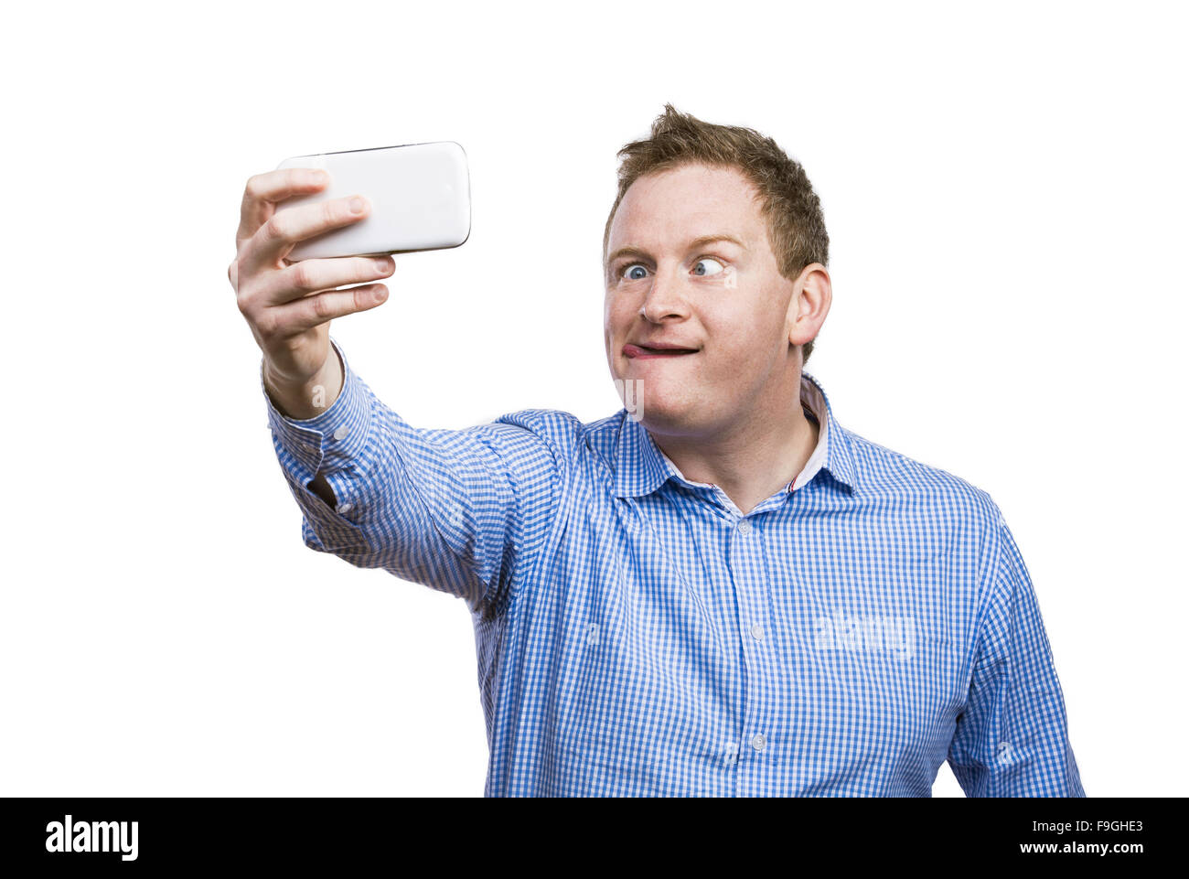 Man making funny faces while taking selfie of himself. Studio shot on white background. Stock Photo