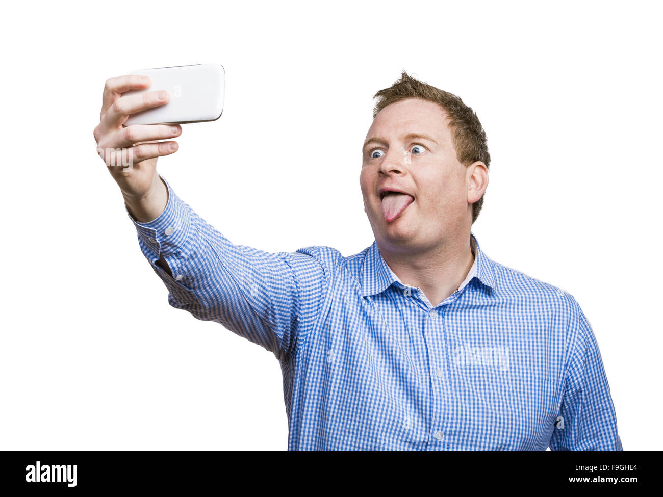 Man making funny faces while taking selfie of himself. Studio shot on white background. Stock Photo