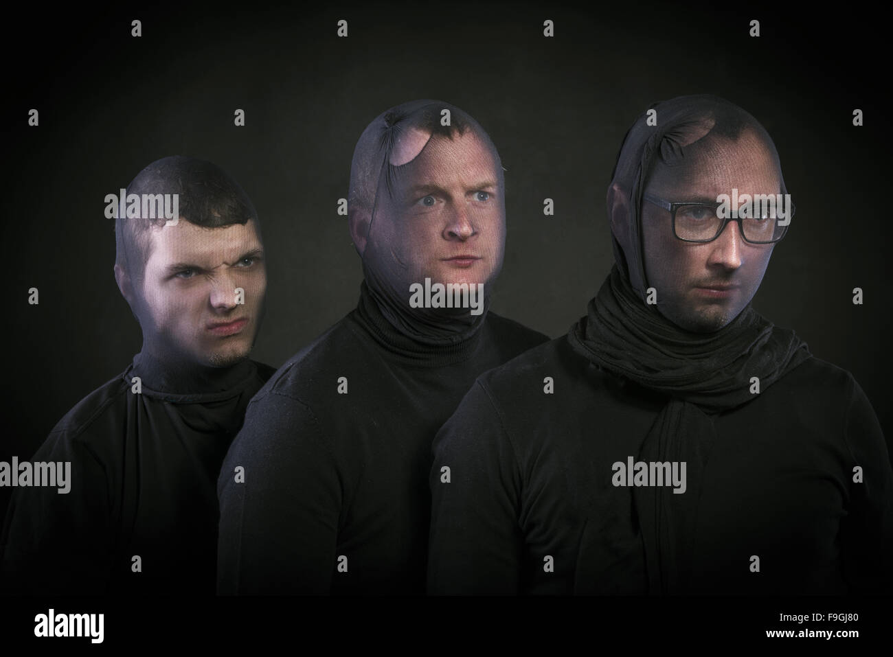 Three thiefs in balaclavas on their faces, dressed in black. Studio