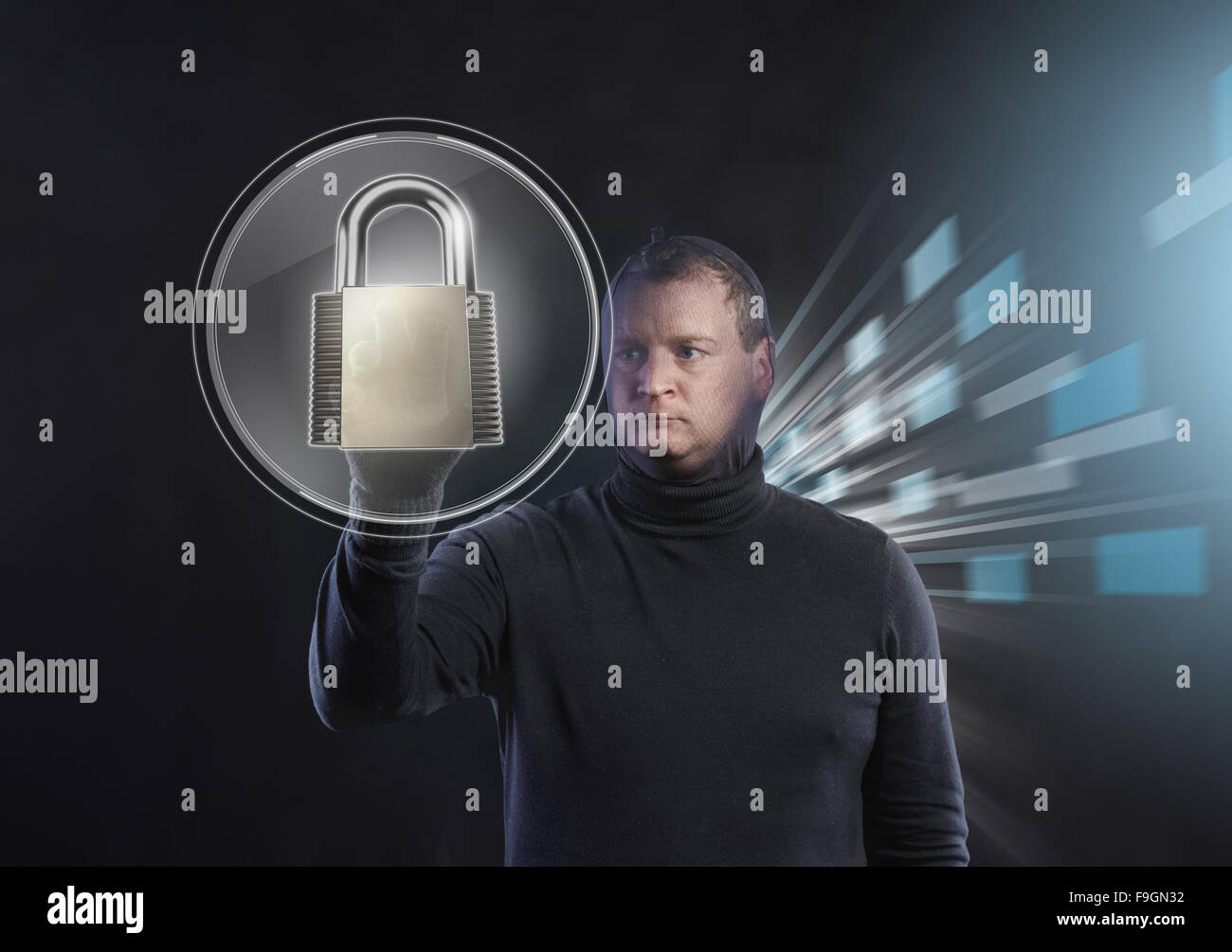 Thief in action stealing information with balaclava on his face, dressed in black. Studio shot on black background. Stock Photo