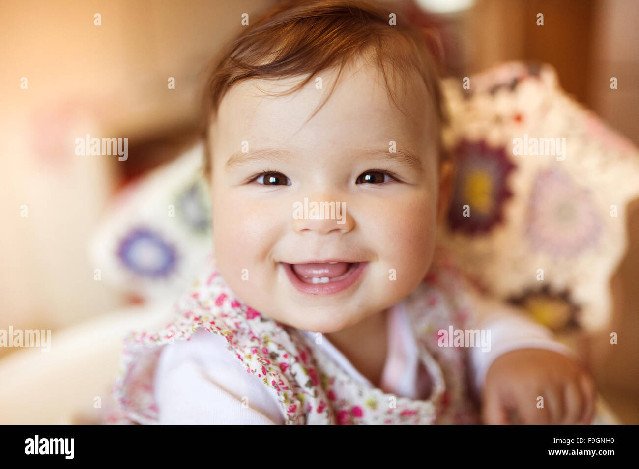 Cute little baby sitting in a high chair happy after being fed by her mother Stock Photo