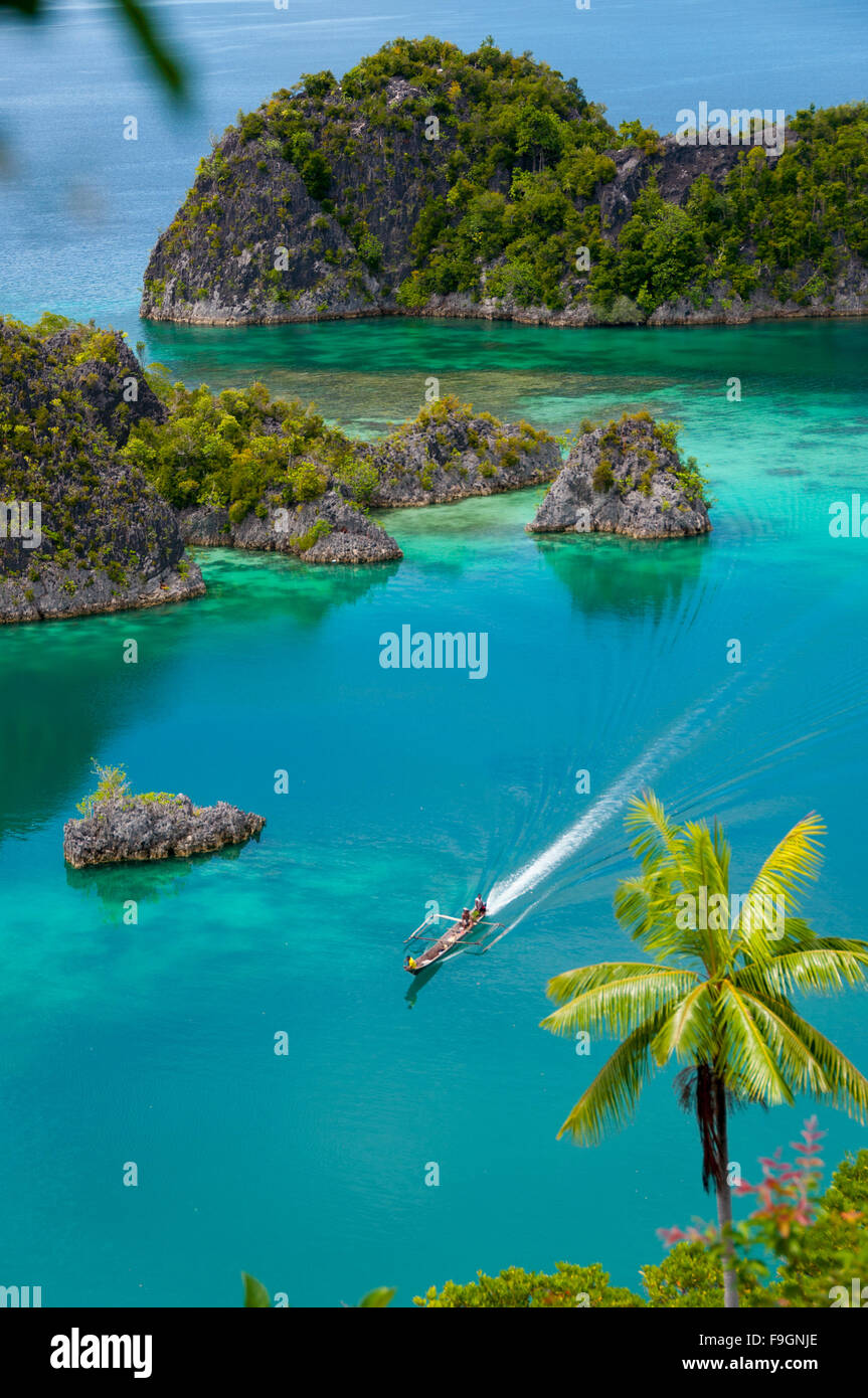 Boat Cruising Around small green Islands belonging to Fam Island in the sea of Raja Ampat, Papua New Guinea Stock Photo