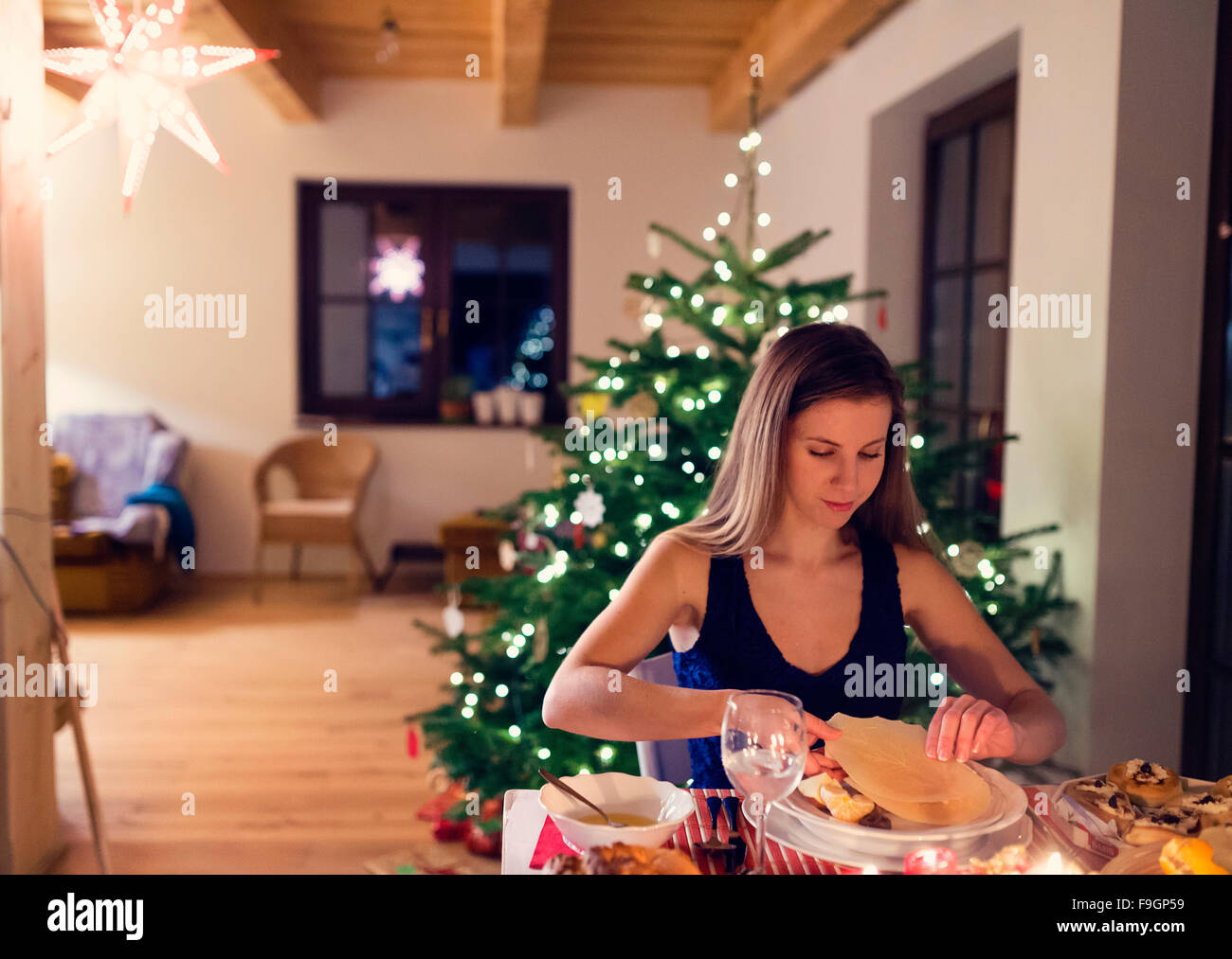 Beautiful young woman eating Christmas meal in her living room Stock Photo