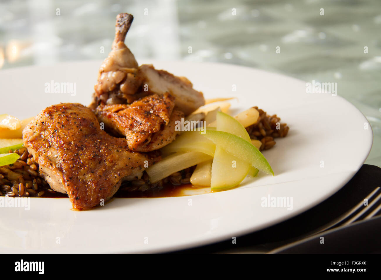 Roasted cornish game hen with toasted rye berries, compressed apple, caramelized salsify, and chartreuse jus Stock Photo