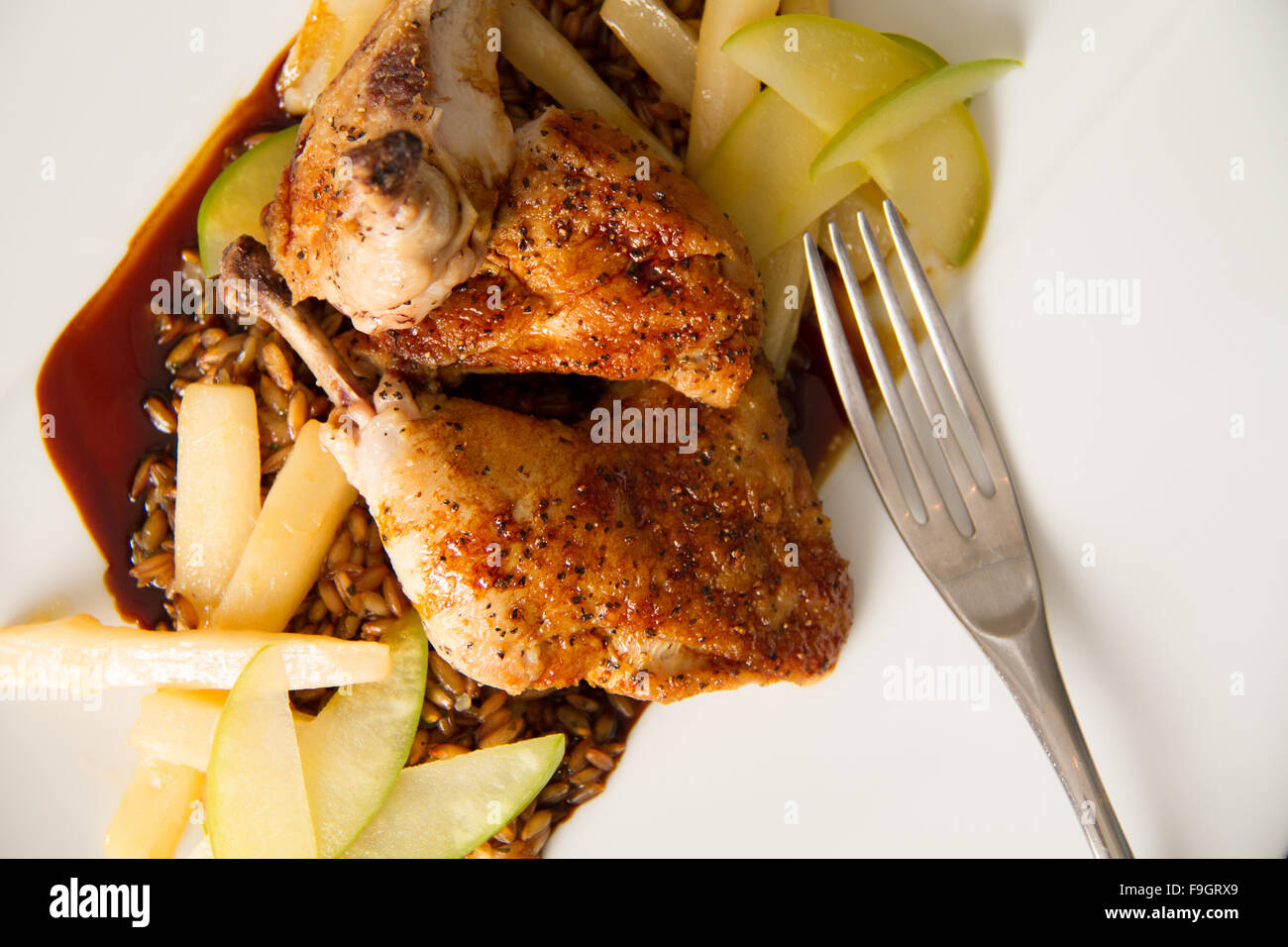 Roasted cornish game hen with toasted rye berries, compressed apple, caramelized salsify, and chartreuse jus Stock Photo