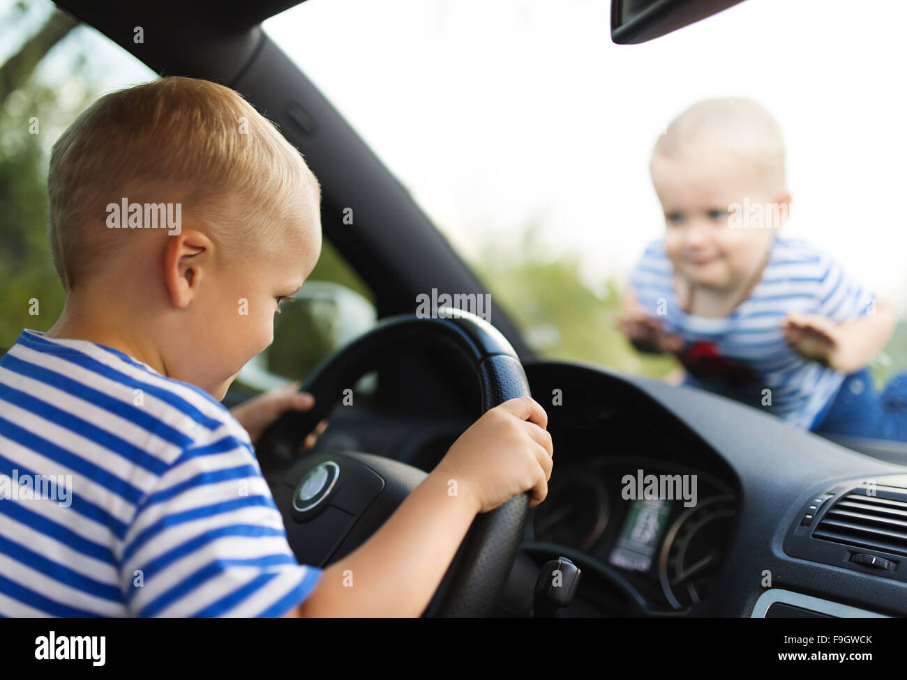 Little boy playing with a steering wheel in a car Stock Photo